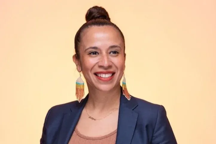 Vanessa Gonzalez-Wright smiling, wearing a navy blazer and beaded earrings.